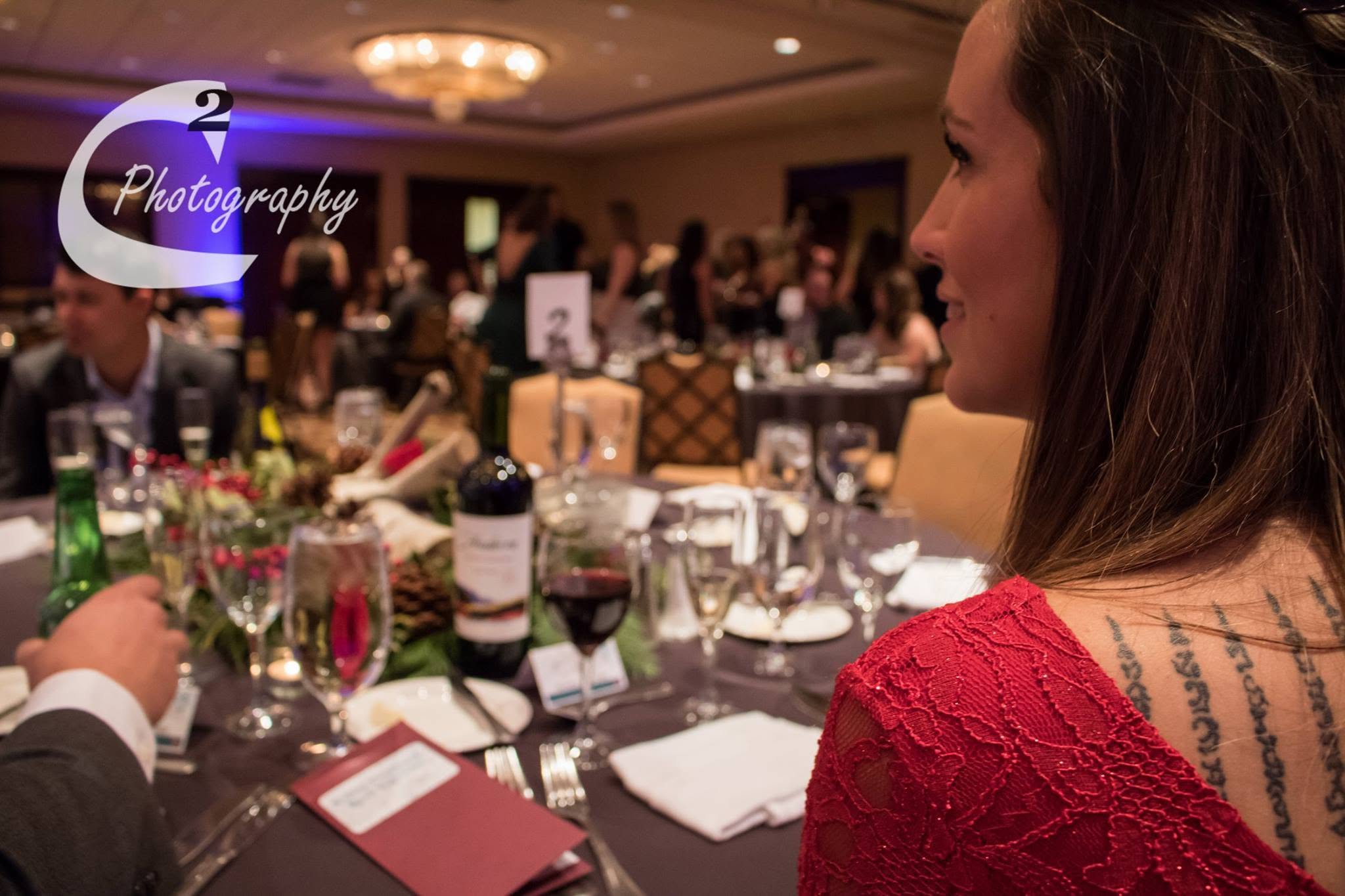Guest in a red dress at an elegant corporate banquet with purple uplighting